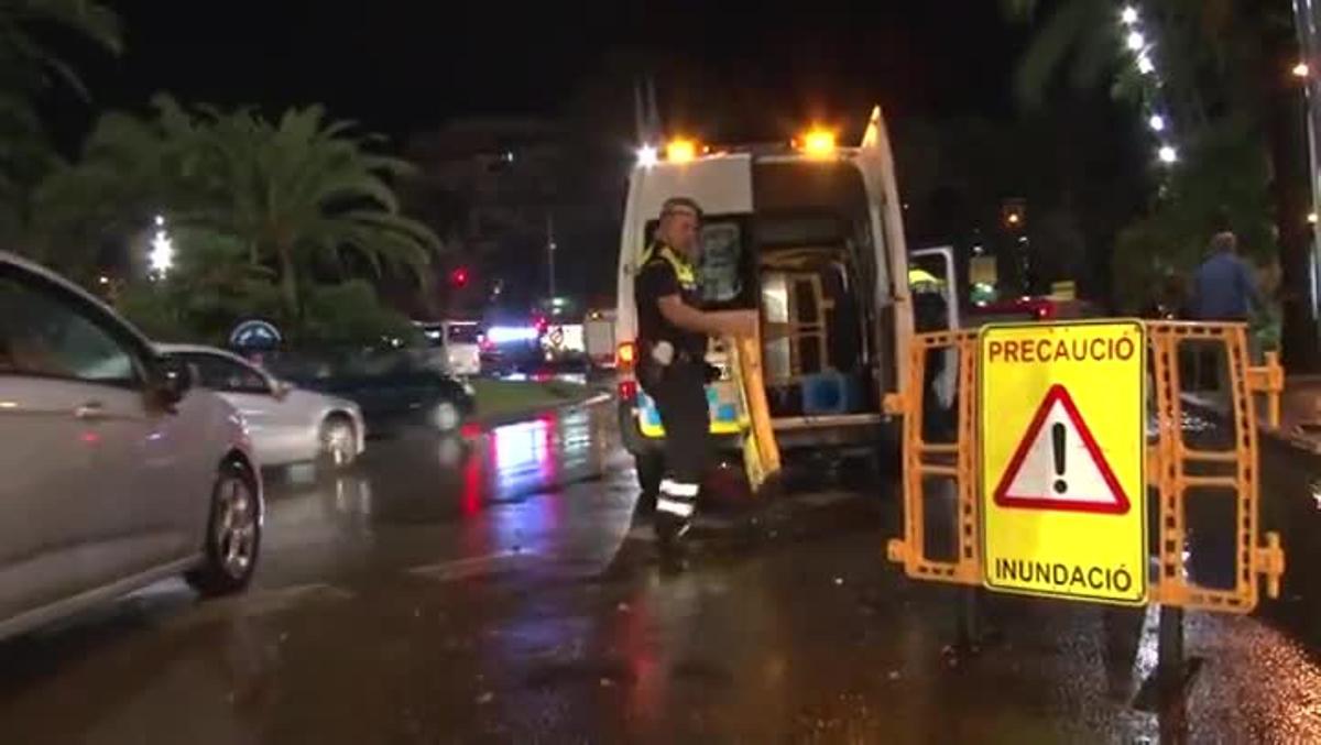 Dues persones caminen descalces per l’acumulació d’aigua a la zona de la plaça Europa de Salou