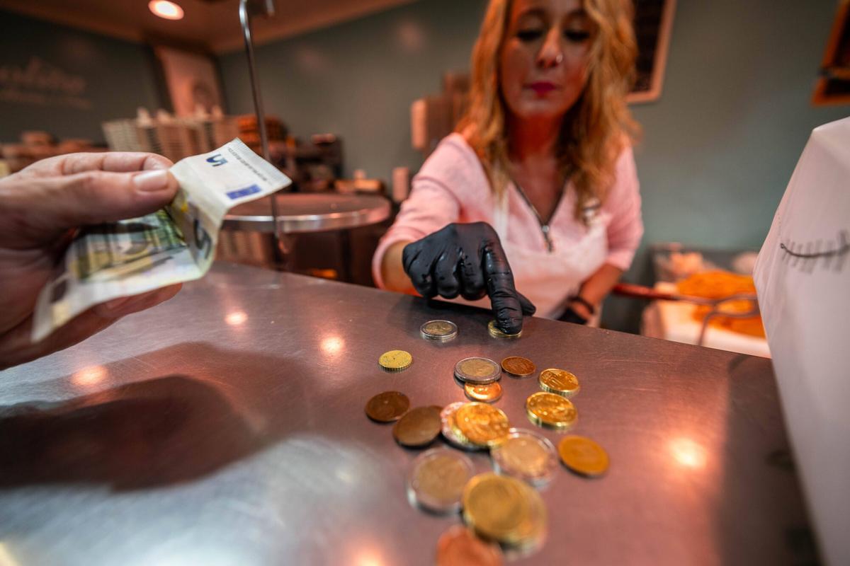 Persona pagando en efectivo, con monedas y billetes.