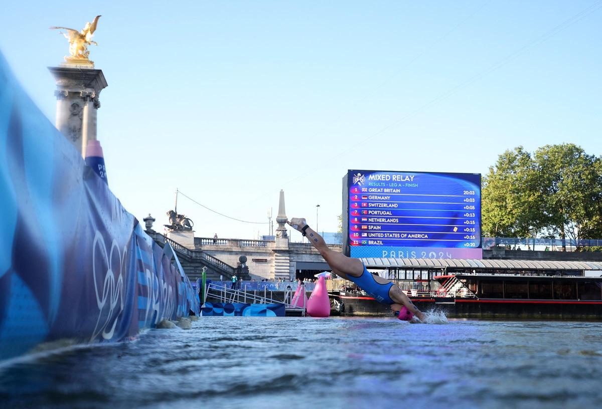 La italiana Alice Betto se zambulle en el río Sena desde el puente de Alejandro III en la prueba de los relevos mixtos del triatlón