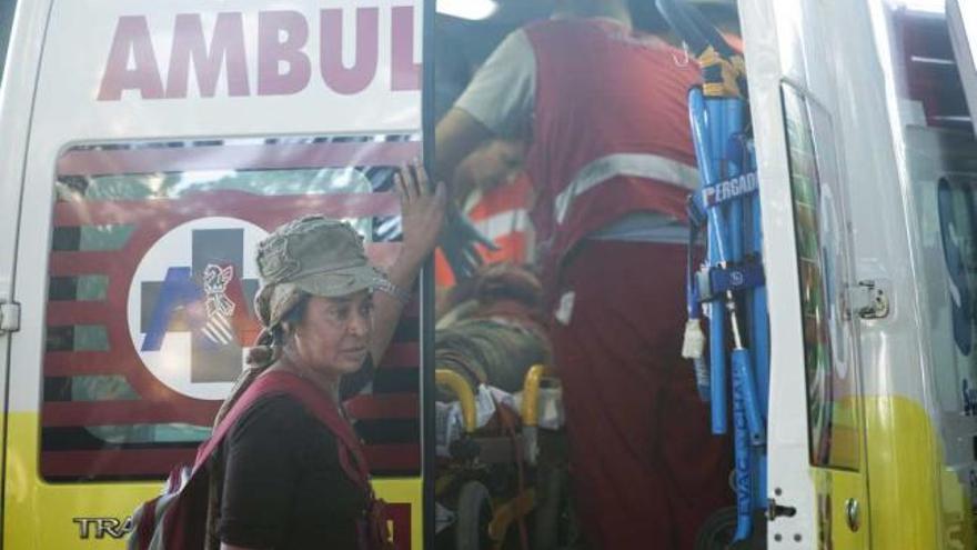 El herido es atendido en la ambulancia mientras una mujer espera fuera.