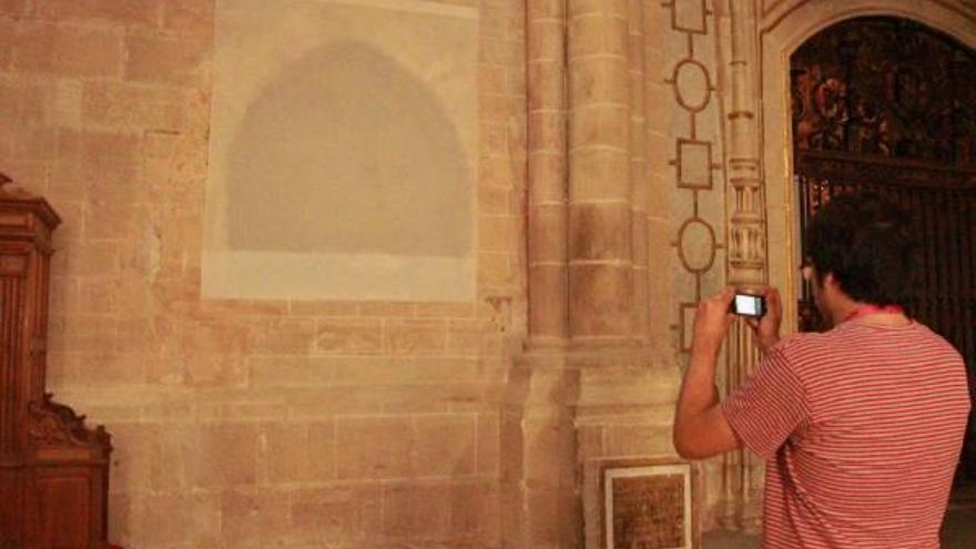 Un turista toma una foto del muro en el que se ha restaurado la escultura yacente del abad Alonso García, del siglo XV.