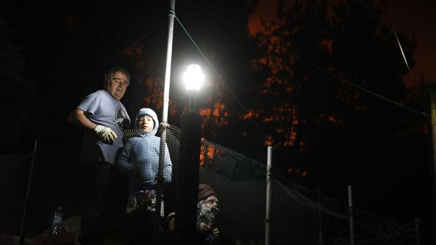Manolo Villaverde y el niño Oliverio Fernández, con las llamas a su espalda en Foyedo (Tineo). | A. G.