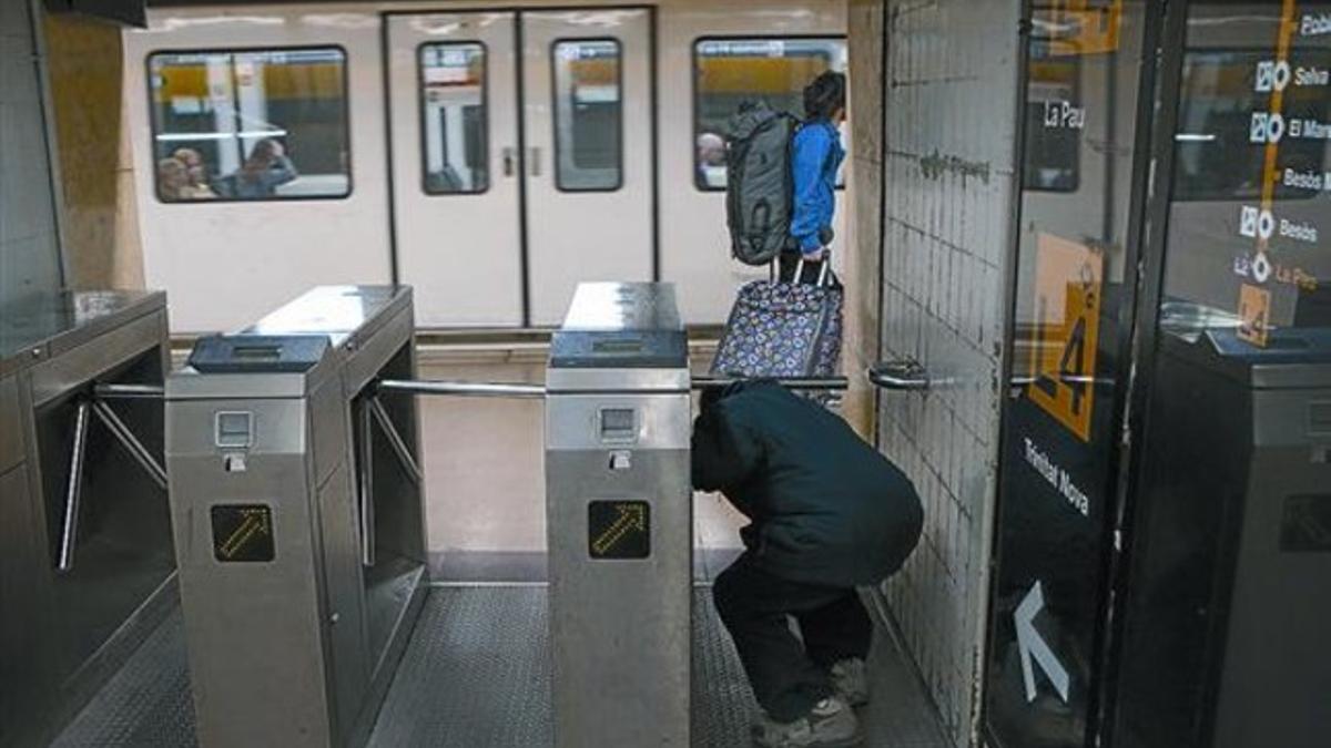 Un hombre pasa, sin validar billete alguno, por debajo de un torniquete de la estación de metro de Jaume I de la L-4, ayer.