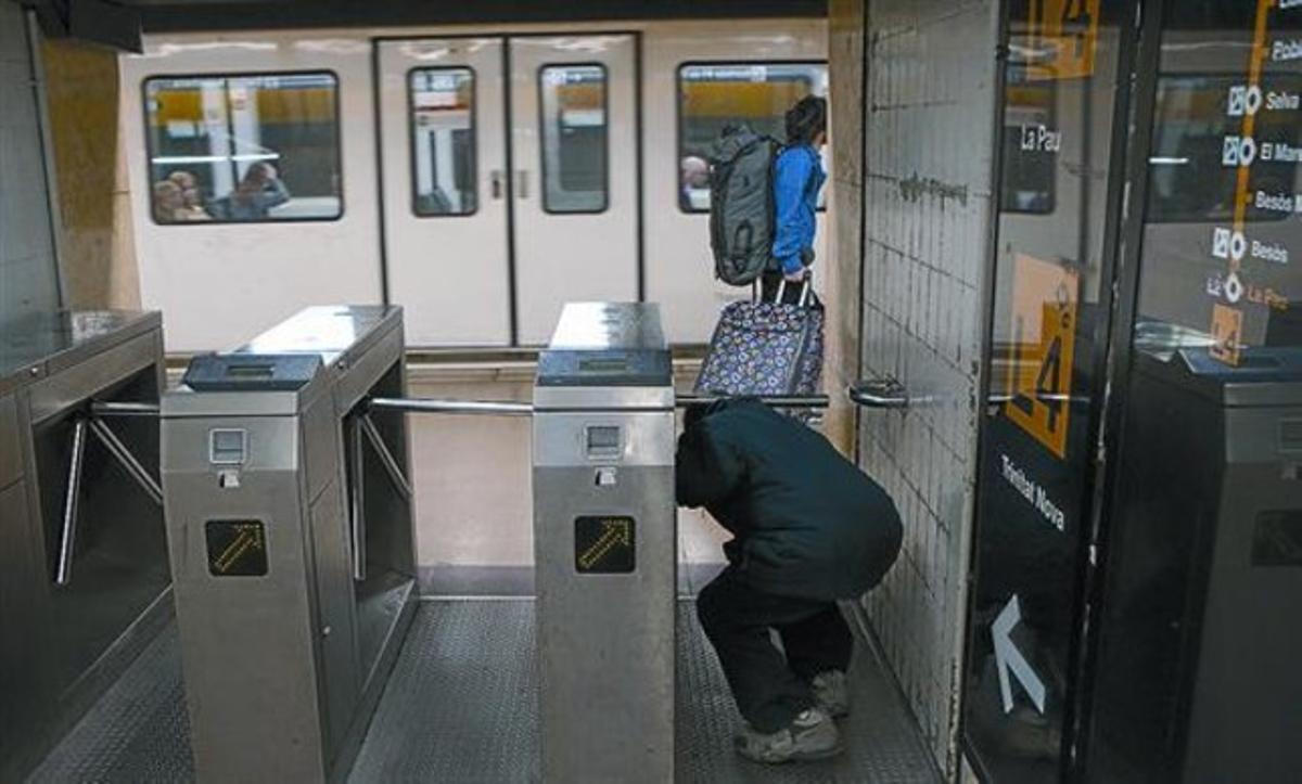 Un hombre pasa, sin validar billete alguno, por debajo de un torniquete de la estación de metro de Jaume I de la L-4, ayer.