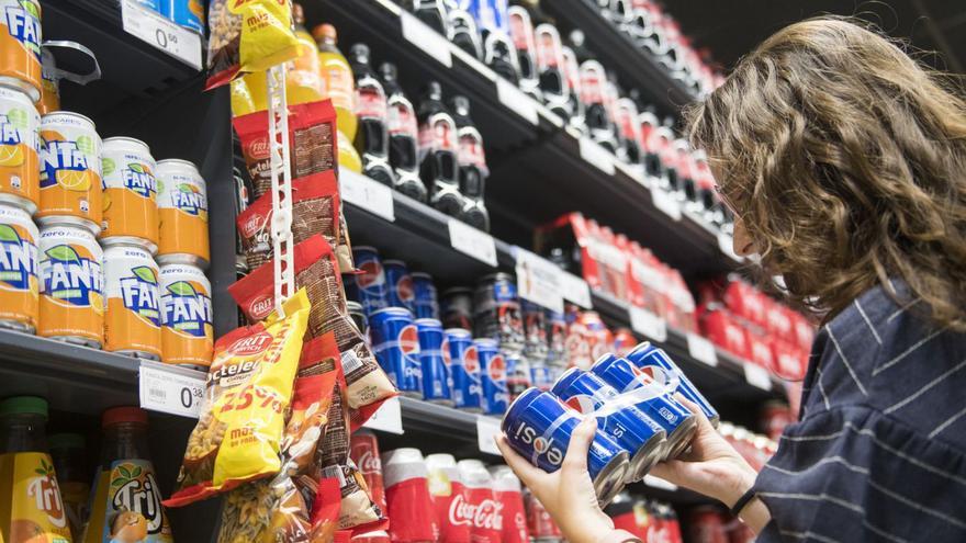 Una mujer, ante los lineales de bebidas azucaradas en un supermercado.   | // JORDI CORTINA