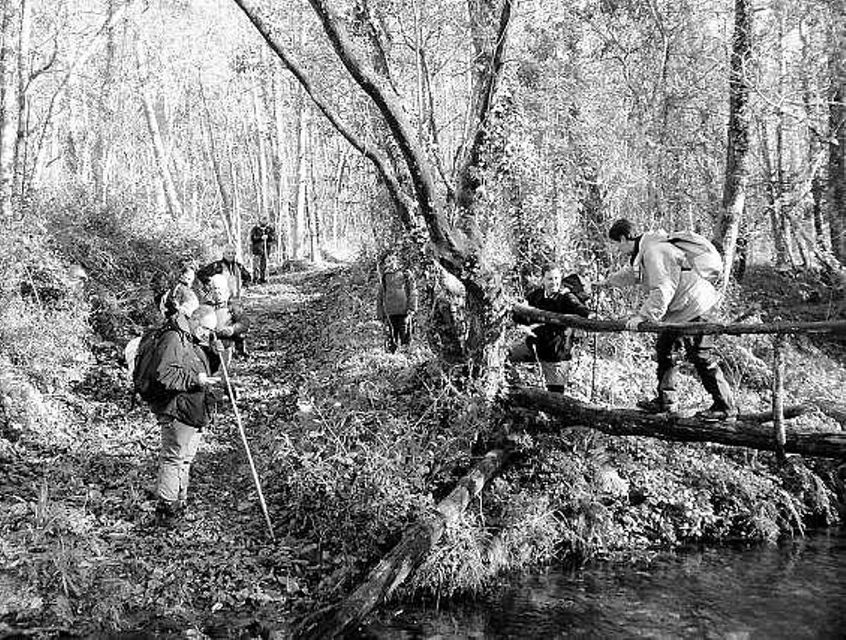 Montañeros del grupo de montaña de Tapia cruzando un puente improvisado sobre el río Berbesa.