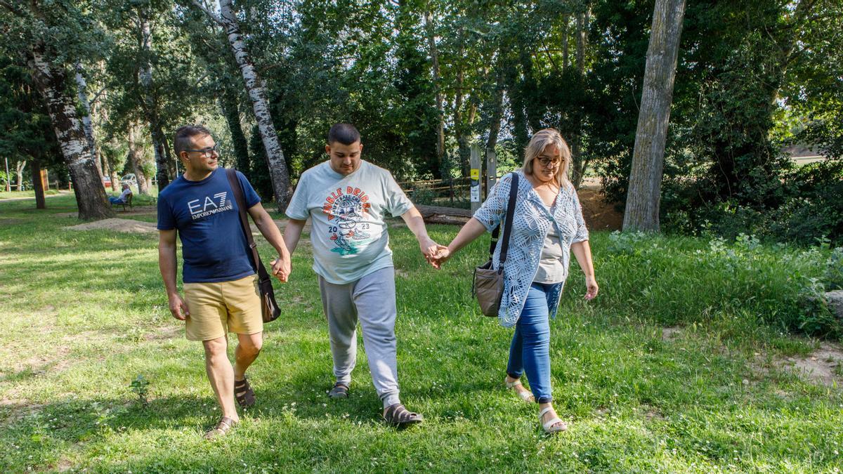 Adrià Lorente, un chico con autismo, pasea por un parque de Cardedeu con sus padres Eva Velàzquez y José Antonio Lorente