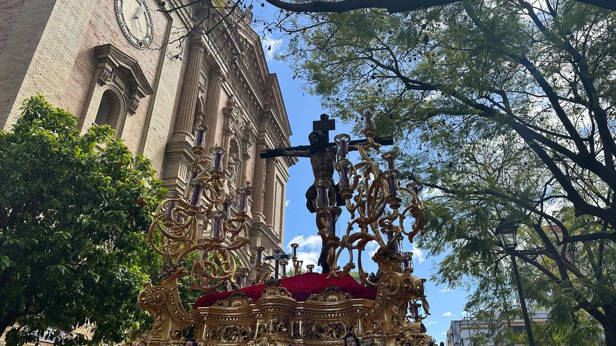 Bajan la cruz del Cristo de la Sed para evitar que toque las ramas de los árboles. Segunda levantá del Cristo en la calle.