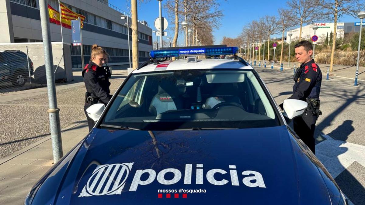 Dos agents dels Mossos d'Esquadra pujant a un vehicle policial