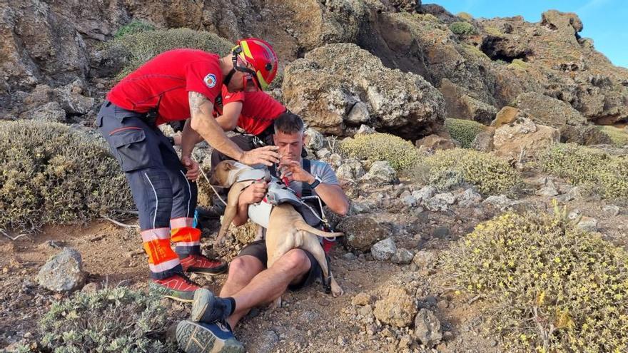 Uno de los senderistas rescatados mantiene al perro entre sus brazos antes de ser izados al helicóptero.