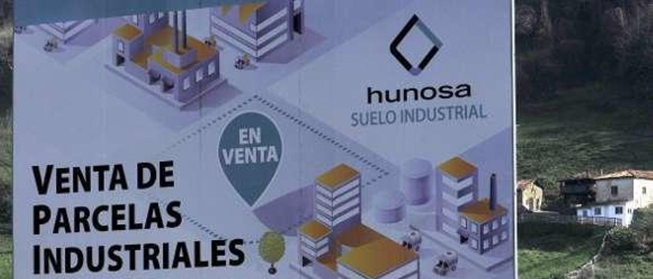 Uno de los operarios que limpian el polígono de Reicastro, junto al cartel que anuncia la venta de las parcelas.