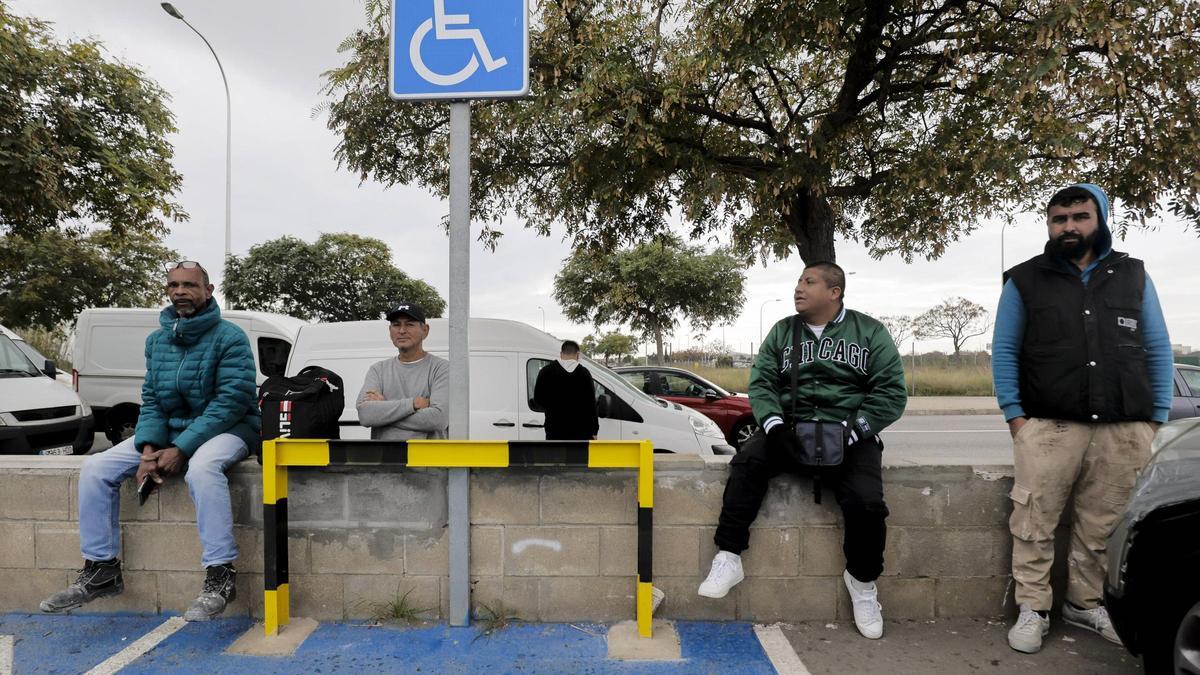 Varios inmigrantes esperan las ofertas de trabajo junto a un centro comercial de construcción en Palma.