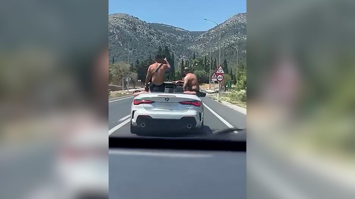 Captados mientras circulan sin camiseta sobre la carrocería de un coche descapotado en la carretera de Valldemossa