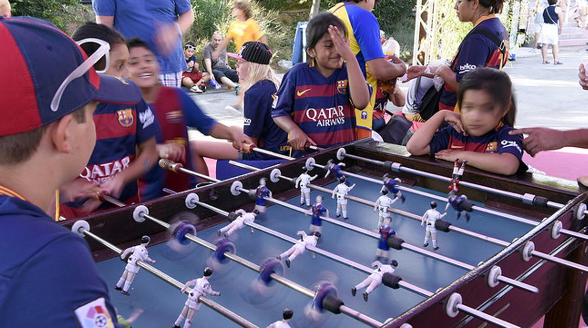 Varios niños se divierten jugando al futbolín en la fiesta del Gamper.
