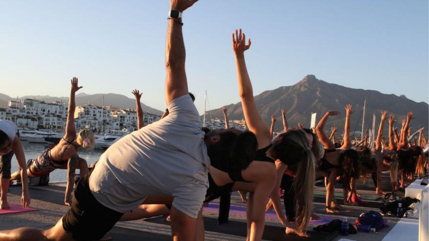 Aficionados al deporte practican yoga en uno de los muelles de Puerto Banús.