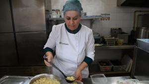 Karima Baouchi, cocinera en la escuela Sol Ixent de Corbins (Segrià), sirve las raciones que luego serán entregadas a los jubilados del pueblo.