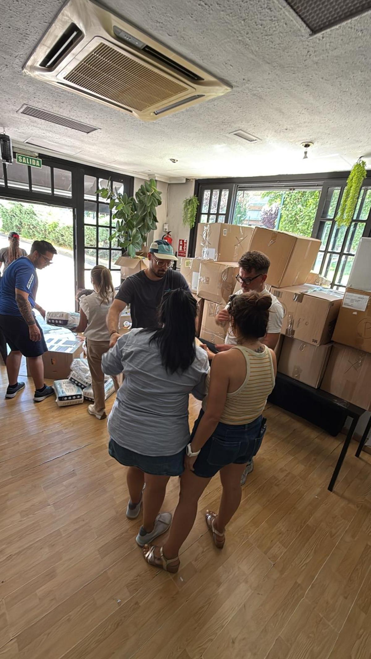 Un grupo de colaboradores de César La Torre cargan en los furgones las cajas de donaciones recogidas en el bar Media Caña de Badajoz.