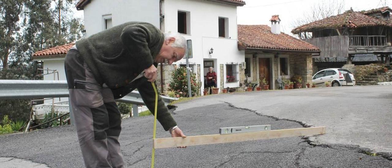 Fernando Menéndez Arango mide el hundimiento de la carretera que afecta a su casa en Los Cabos (Pravia).