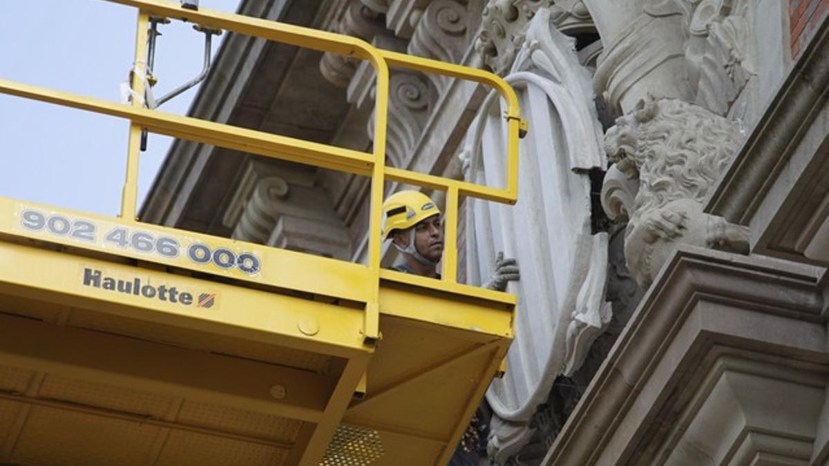 Un operario coloca el nuevo blasón del Parlamente, en una de las pruebas de esta mañana.