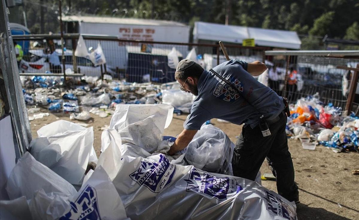 Un agente de policía israelí inspecciona bolsas llenas de objetos personales de los participantes en la celebración, recogidos tras la avalancha. 