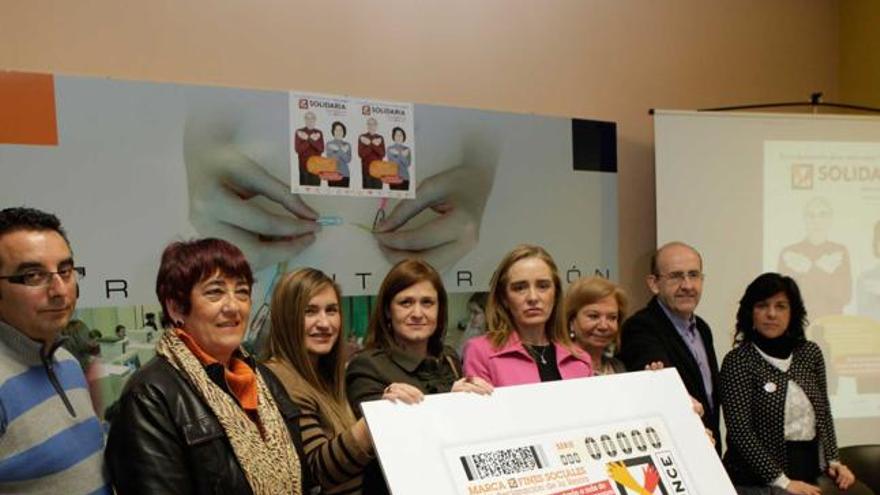 De izquierda a derecha, Marcos Gabarre, Cristina Sariego, Mónica Oviedo, Yobanka Cuervo, Matilde Gómez, María Antonia Fernández, José Luis Crespo y Loreto Ventosa, posando con la imagen del cupón de la ONCE.