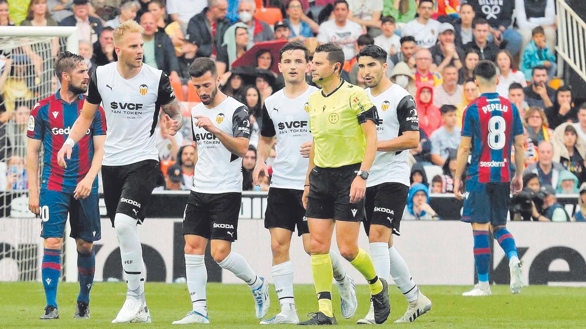 Los jugadores del Valencia protestan a Figueroa Vázquez durante el Derbi