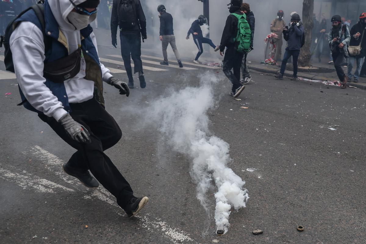 Paris (France), 23/03/2023.- A protester tries to catch a tear gas bomb during clashes with anti-riot police, during a protest against government pension reform in Paris, France, 23 March 2023. Protests continue in France after the French prime minister announced on 16 March 2023 the use of Article 49 paragraph 3 (49.3) of the French Constitution to have the text on the controversial pension reform law be definitively adopted without a vote in the National Assembly (lower house of parliament). The bill would raise the retirement age in France from 62 to 64 by 2030. (Protestas, Francia) EFE/EPA/MOHAMMED BADRA