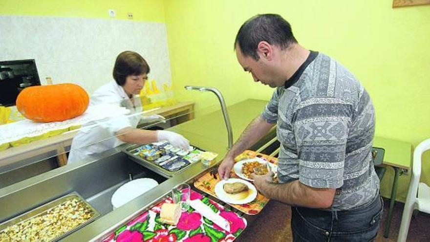 Un usuario del comedor social de Amicos, atendido por una voluntaria.