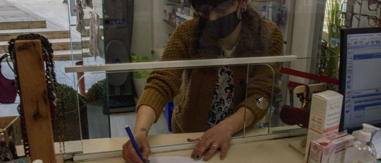 La clienta de una farmacia del centro de Oviedo firma contra el traslado de la Escuela. | Jaime Casanova