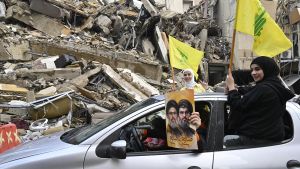 Dos chicas ondean banderas de Hizbulá y otra persona muestra una foto de Hasán Nasrala en una calle de Beirut, celebrando el alto el fuego.