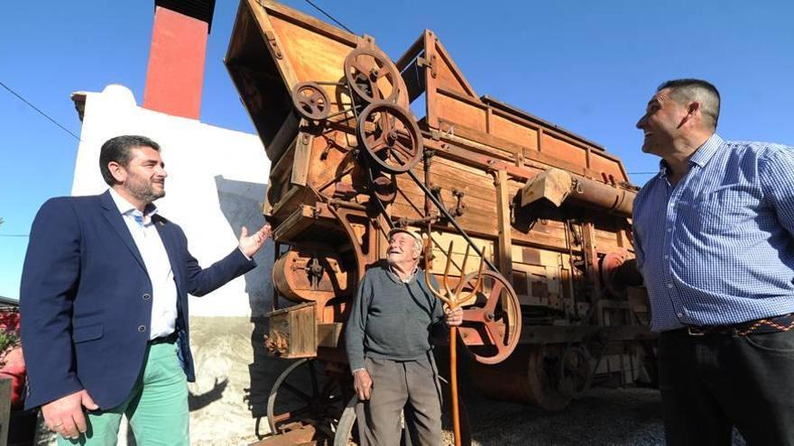 Joaquín Belmonte (derecha) muestra la trilladora de su familia junto a su padre, Juan Antonio Belmonte (centro) y el pedáneo de Los Dolores, Pedro Morales.