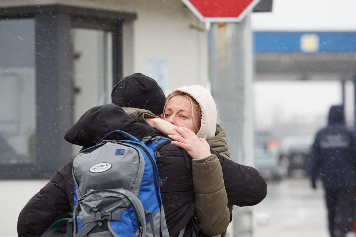 Una pareja se abraza mientras refugiados ucranianos esperan un transporte en el puesto de control de la frontera entre Moldavia y Ucrania
