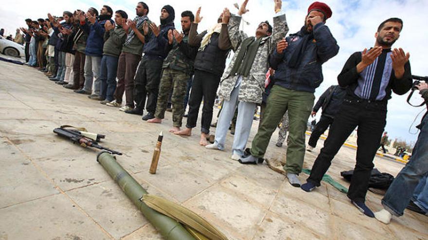 Diversos rebels preguen davant les seves armes a la localitat líbia de Bin Jawad.