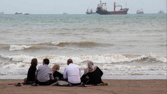 Ciutadans iranians asseguts a la vora de l’estret d’Ormuz, l’abril passat. | RAZIEH POUDAT / AFP