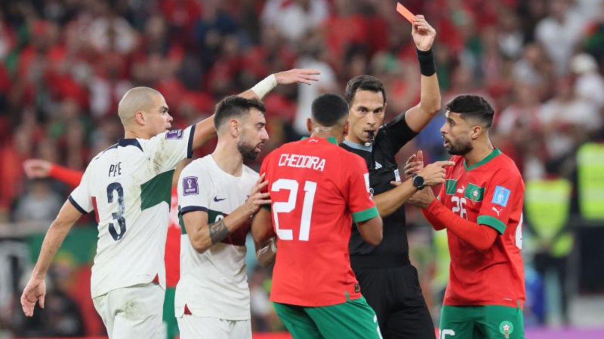 Facundo Tello muestra una cartulina amarilla a Walid Cheddira, jugador de Marruecos, en el encuentro ante Portugal en el Mundial de Qatar