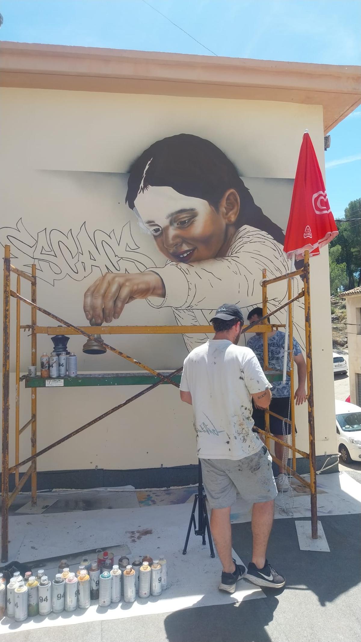 El artista Nart One pintando un mural en el colegio de Santa Anna de Oliva