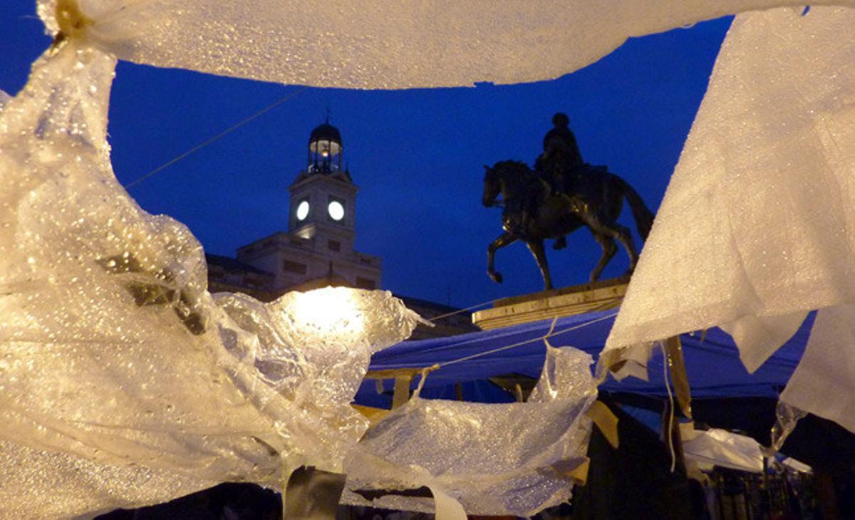 L’estàtua eqüestre de Carlos III i la Casa de Correos vistos a través dels plàstics que cobreixen milers d’’indignats’ a la madrilenya Puerta del Sol al fer-se de dia.