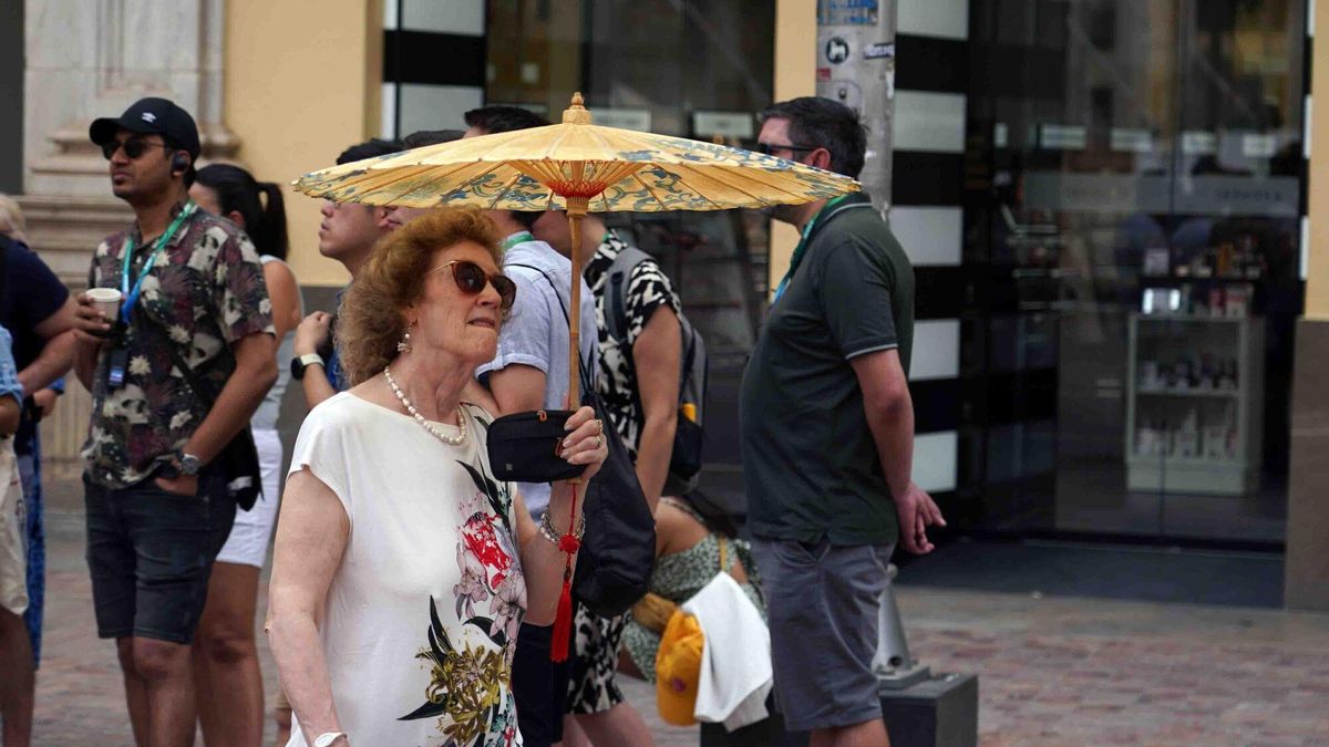 Una mujer se resguarda del calor con un paraguas en Málaga.