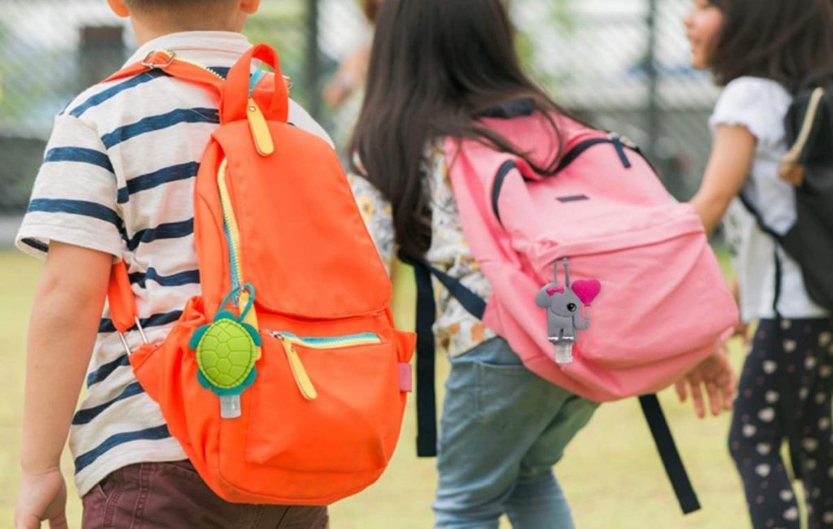 Niños con mochilas camino al colegio.