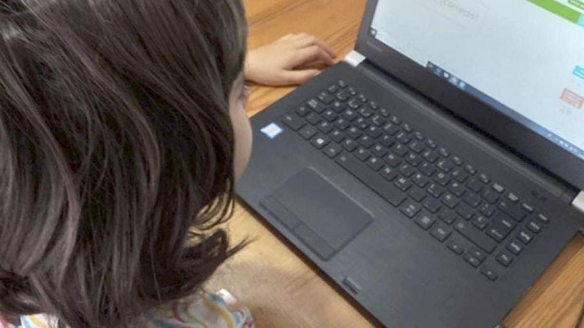 Una niña realizando tareas escolares desde un ordenador portátil.