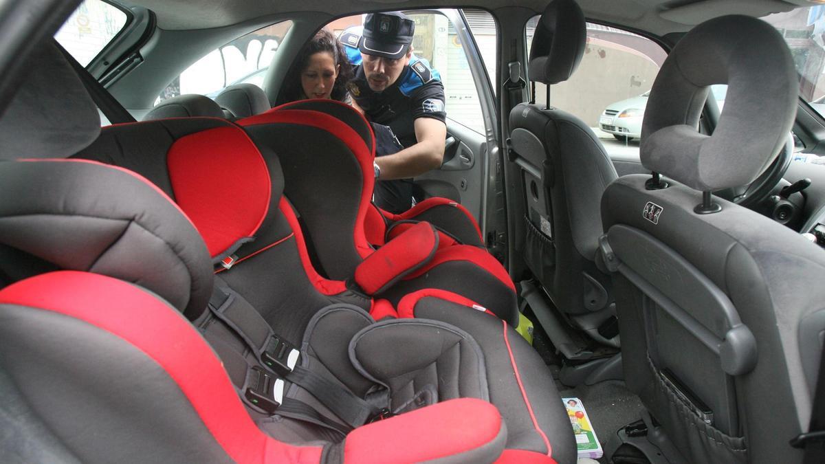 Un agente de la Policía Local de Vigo revisando las sillas infantiles de un coche. // FDV