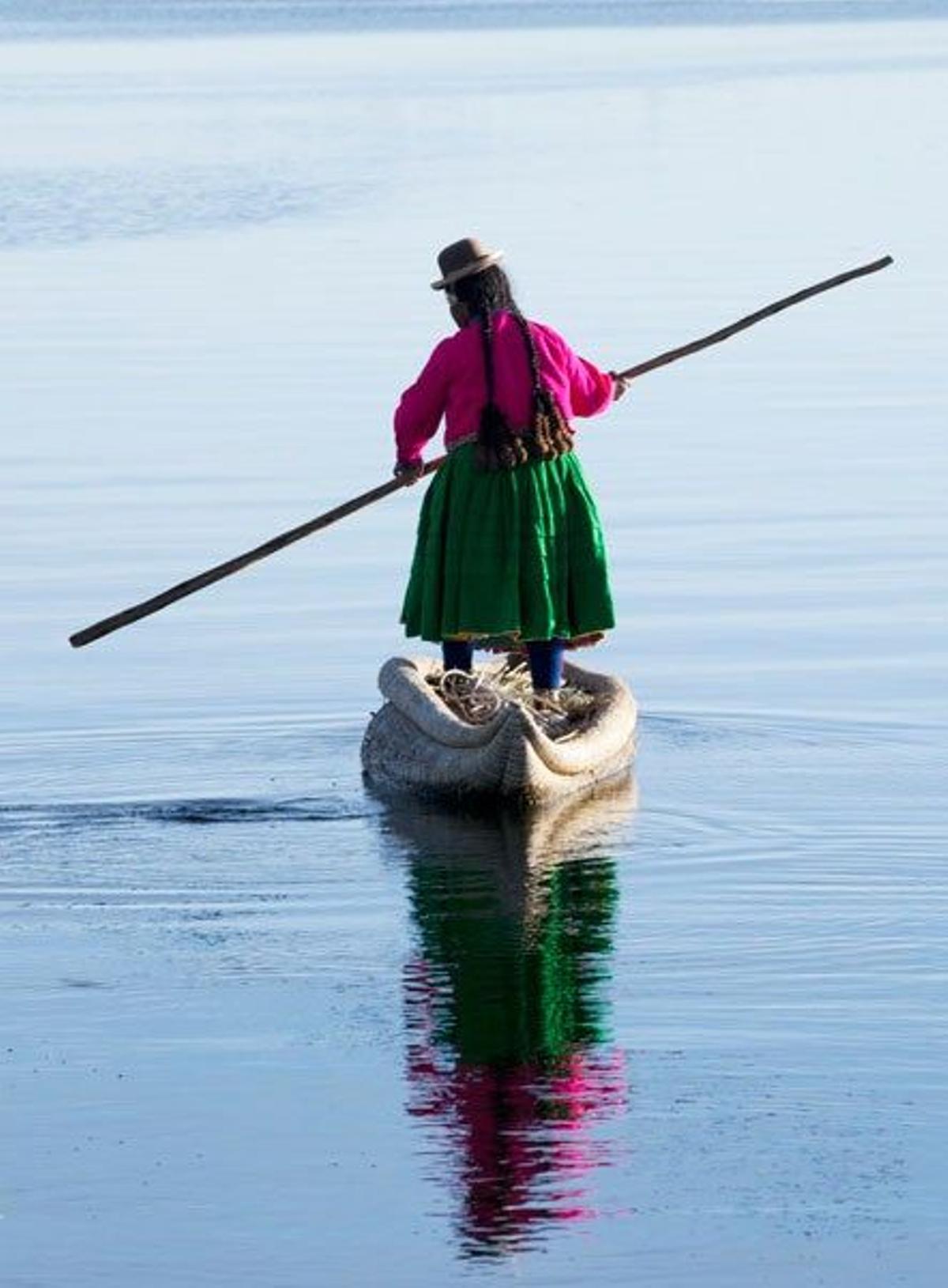 Mujer vestida con ropas tradicionales sobre un barco tradicional en el Lago Titicaca, entre Bolivia y Perú.