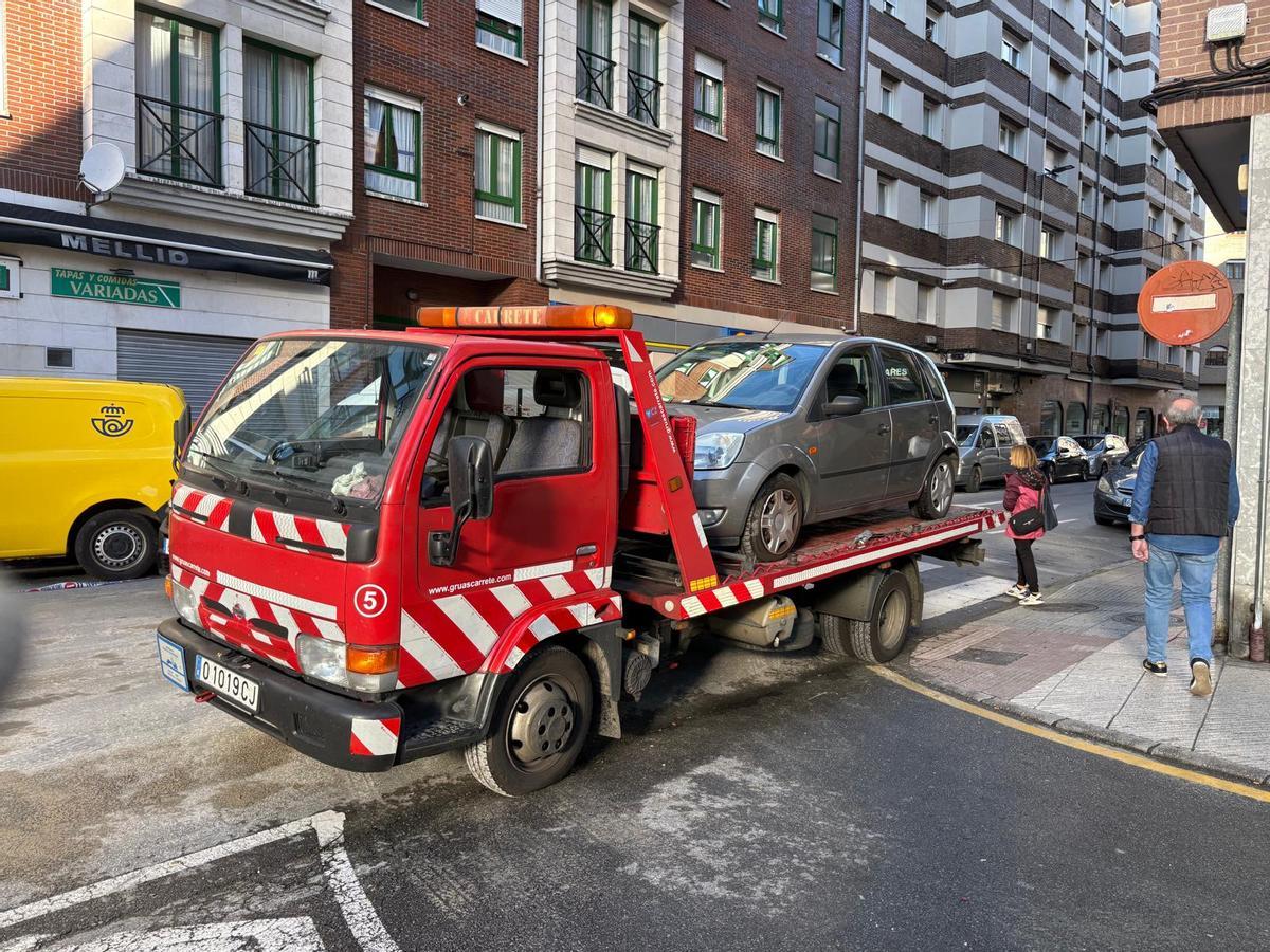 Una grúa llevándose uno de los coches siniestrados en el accidente de La Felguera