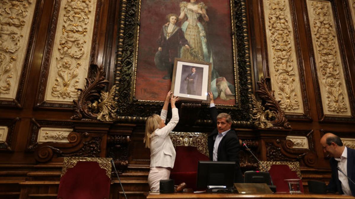 Alberto Fernández Díaz sostiene una foto del rey Felipe en el lugar donde estaba el busto del rey Juan Carlos, este viernes en el Ayuntamiento de Barcelona.