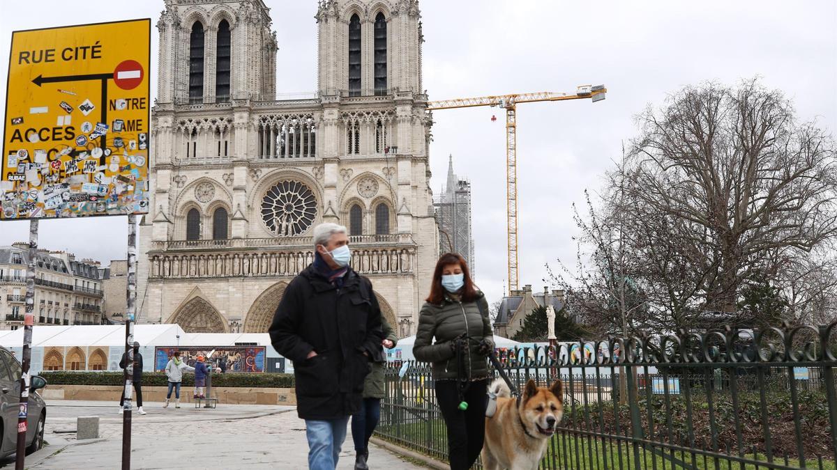 Un pareja con mascarilla camina por las inmediaciones de la catedral de Notre Damme de París.