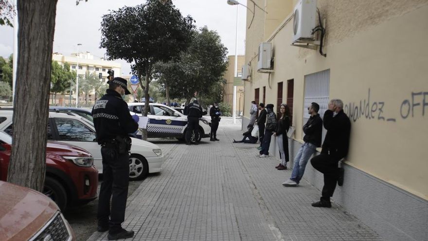 Un agente trata de identificar en Alicante a sujetos reunidos en la calle pese al Estado de Alarma.