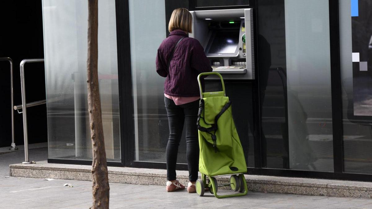 Una mujer consulta su cuenta en un cajero automático del centro de Murcia.