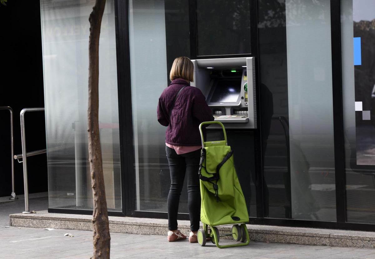 Una mujer consulta su cuenta en un cajero automático del centro de Murcia.