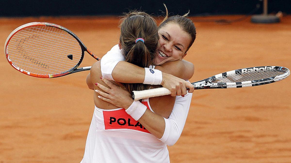 La polacas Agnieszka Radwanska (de espaldas) y Alicja Rosolska se abrazan tras vencer en el partido de dobles, quinto y definitivo de la eliminatoria de la Copa Federación, a las españolas Silvia Soler y Anabel Medina