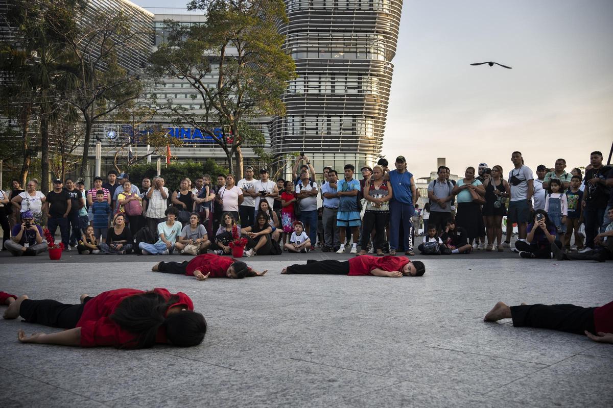 Varias jóvenes bailarinas tumbadas en el suelo en la plaza del centro de San Salvador.